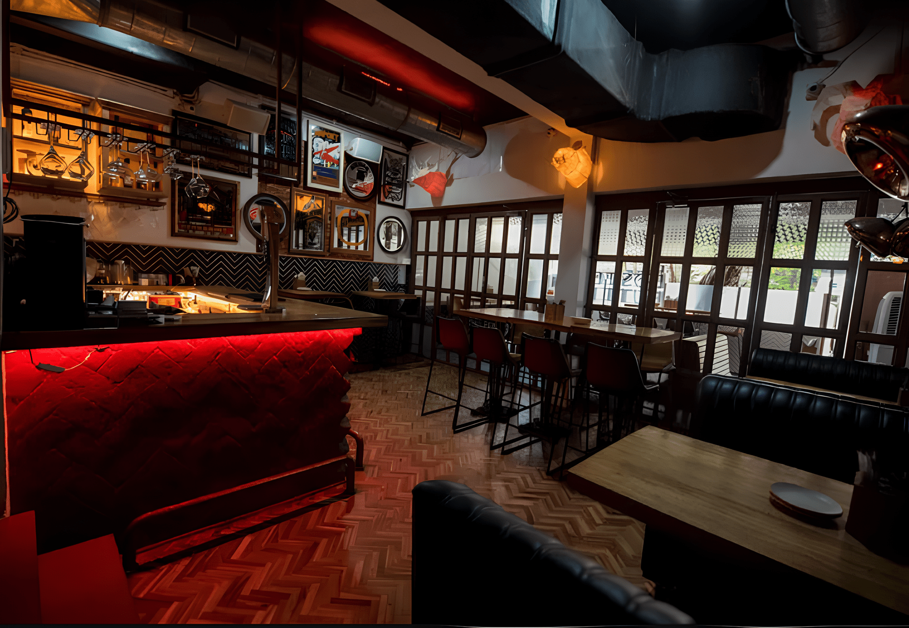 A comfy, empty bar with red highlights and wood flooring.