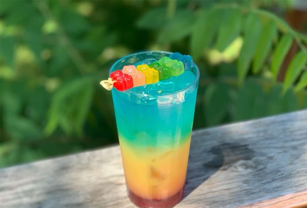 Gummy Bear Rainbow Cocktail shows off its vibrant gradient in two ways — the colorful drink itself and the chain of gummy bears that make the perfect garnish