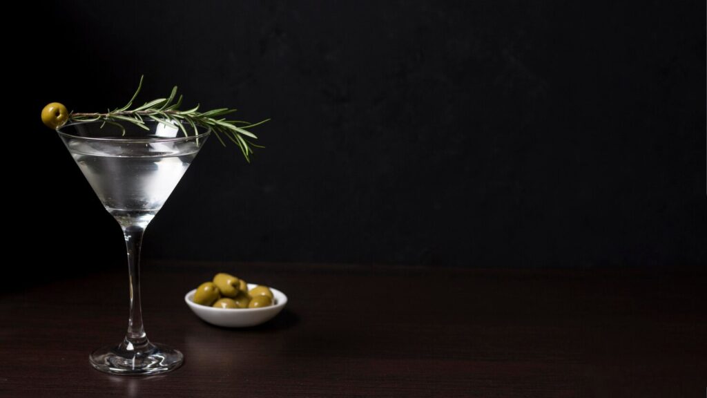 A glass of Martini served with an olive garnish.