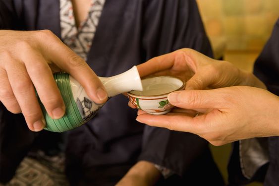 Sake being poured into a Japanese drinking cup