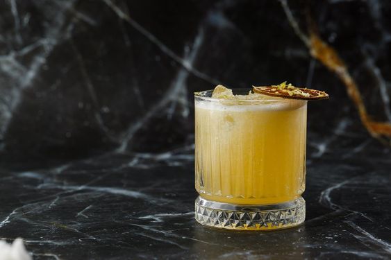 A glass of Mezcalita, garnished with a dried citrus wheel.