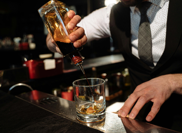 A bartender making a glass of whisky